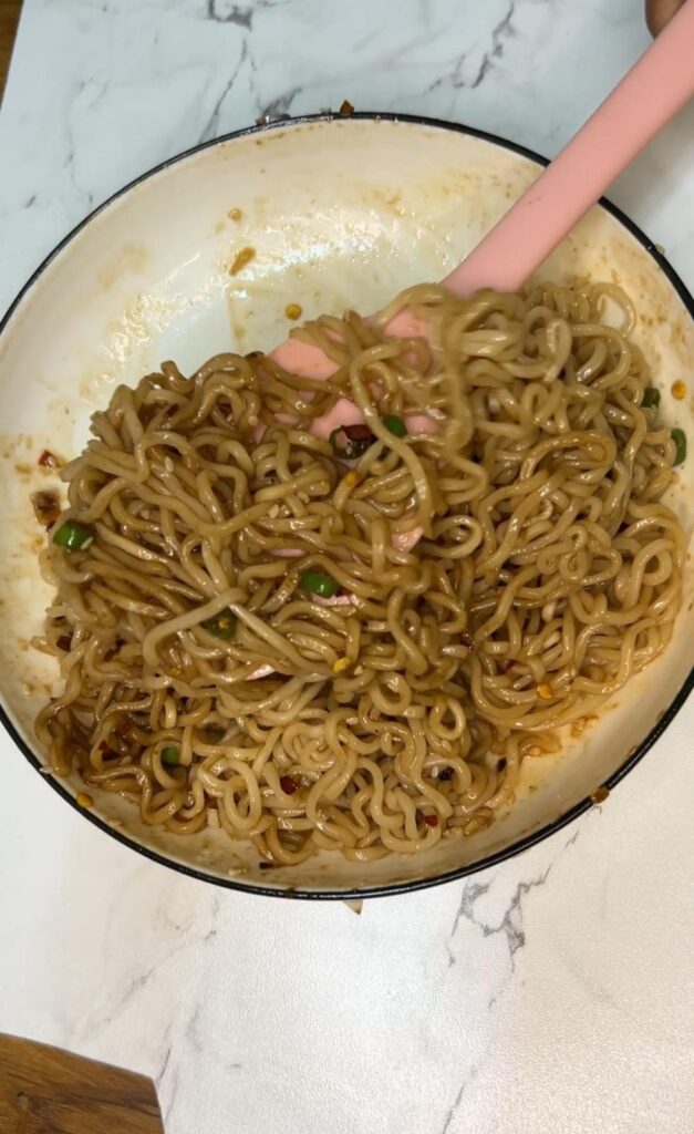 A bowl of spicy chili oil noodles recipe topped with garlic, scallions, and sesame seeds, served fresh and steaming.