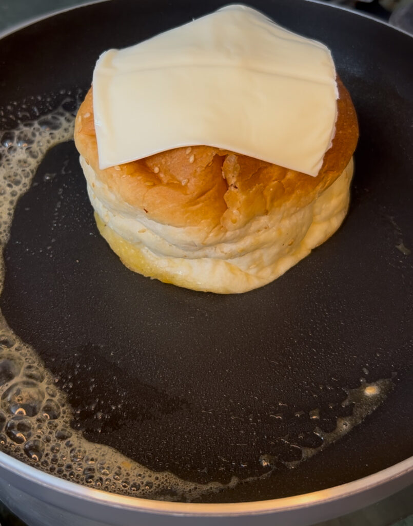 Stack of cheesy vegetable buns on a wooden board garnished with herbs