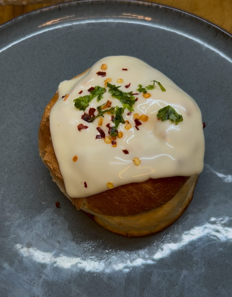 Close-up of freshly baked cheesy vegetable bun with golden crust and gooey cheese