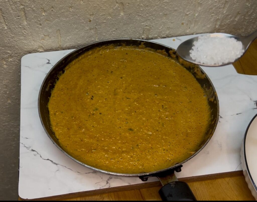Spoonful of creamy tofu curry being served from a one-pot dish