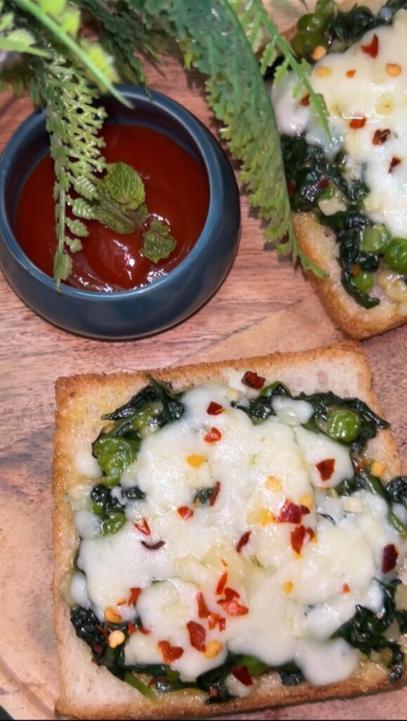 Crispy spinach toast topped with melted cheese on a white plate