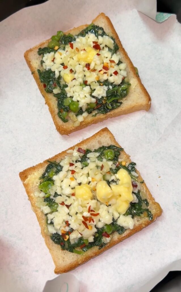 Sliced spinach toast on a wooden board with garlic and herbs