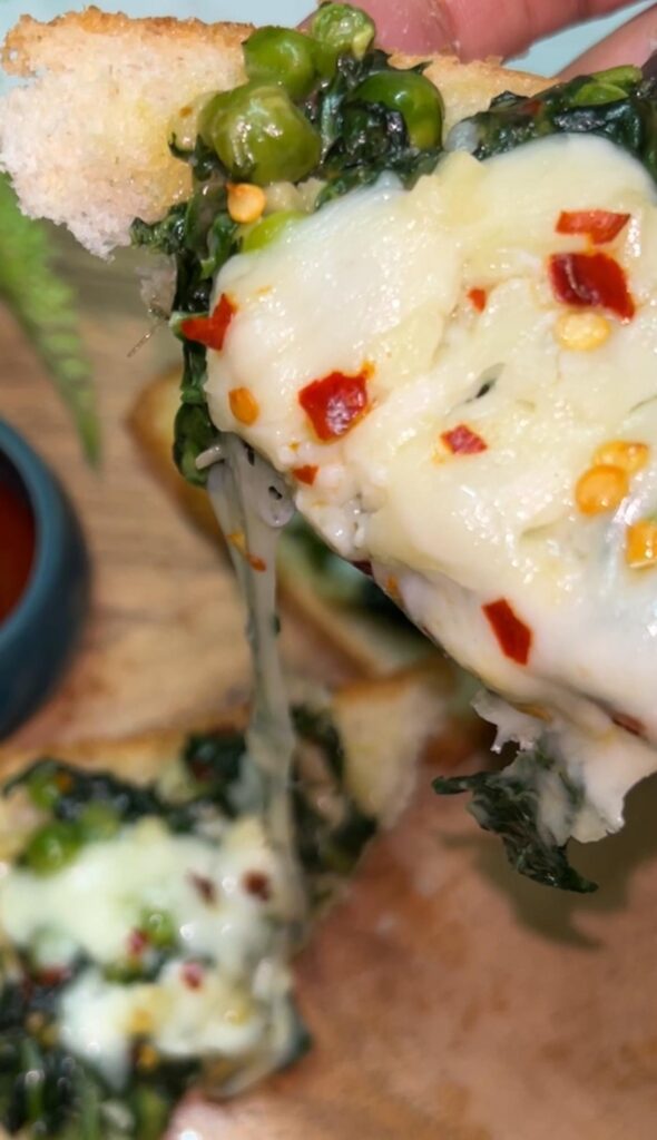 Sliced spinach toast on a wooden board with garlic and herbs