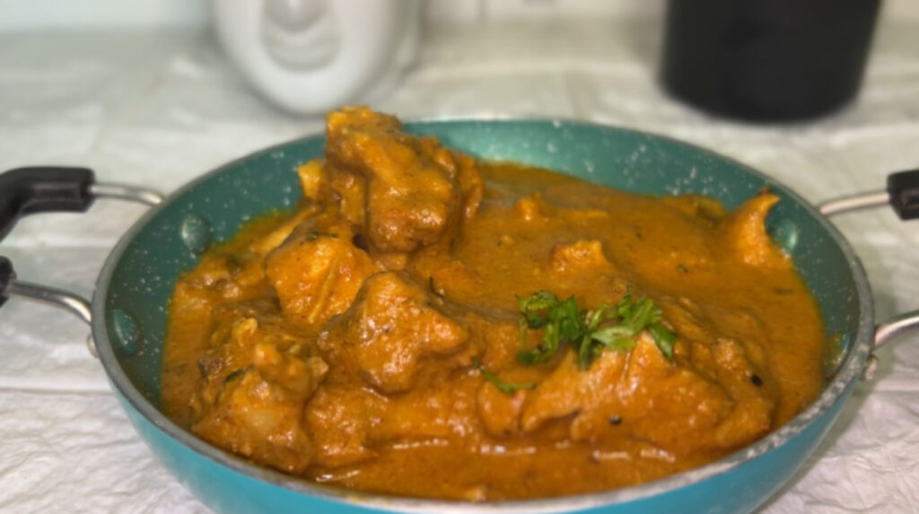 Close-up shot of creamy butter chicken served with naan bread