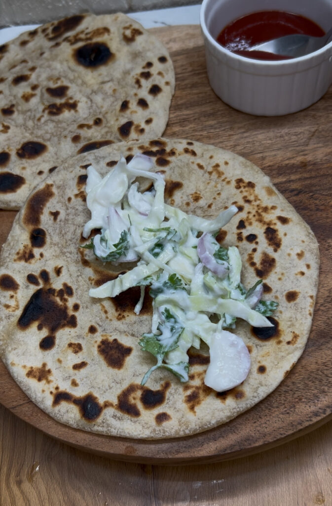 Tortilla chicken wrap with colorful veggies on a wooden plate